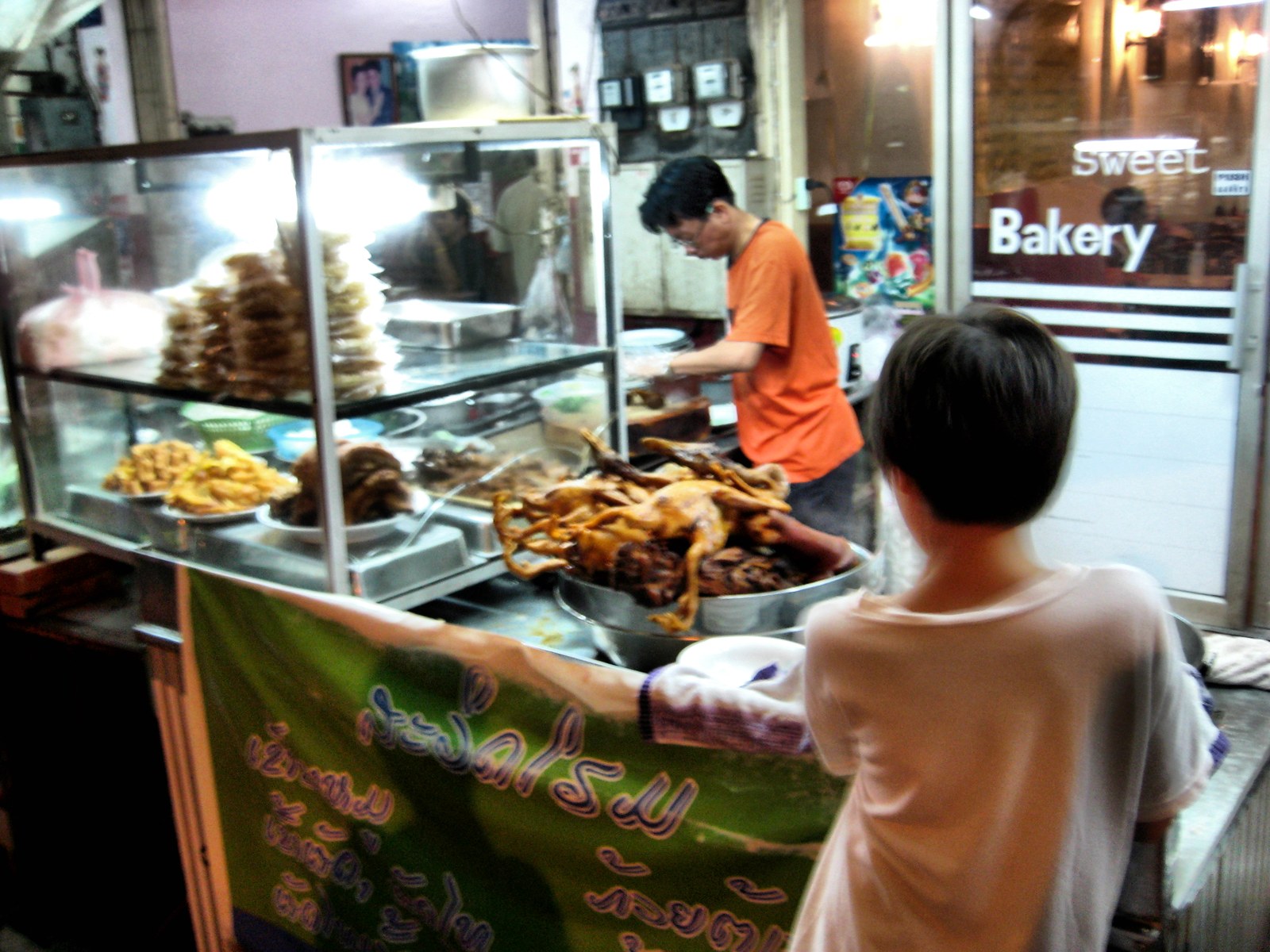 Night market food stall with prepared dishes and late-evening crowd energy.