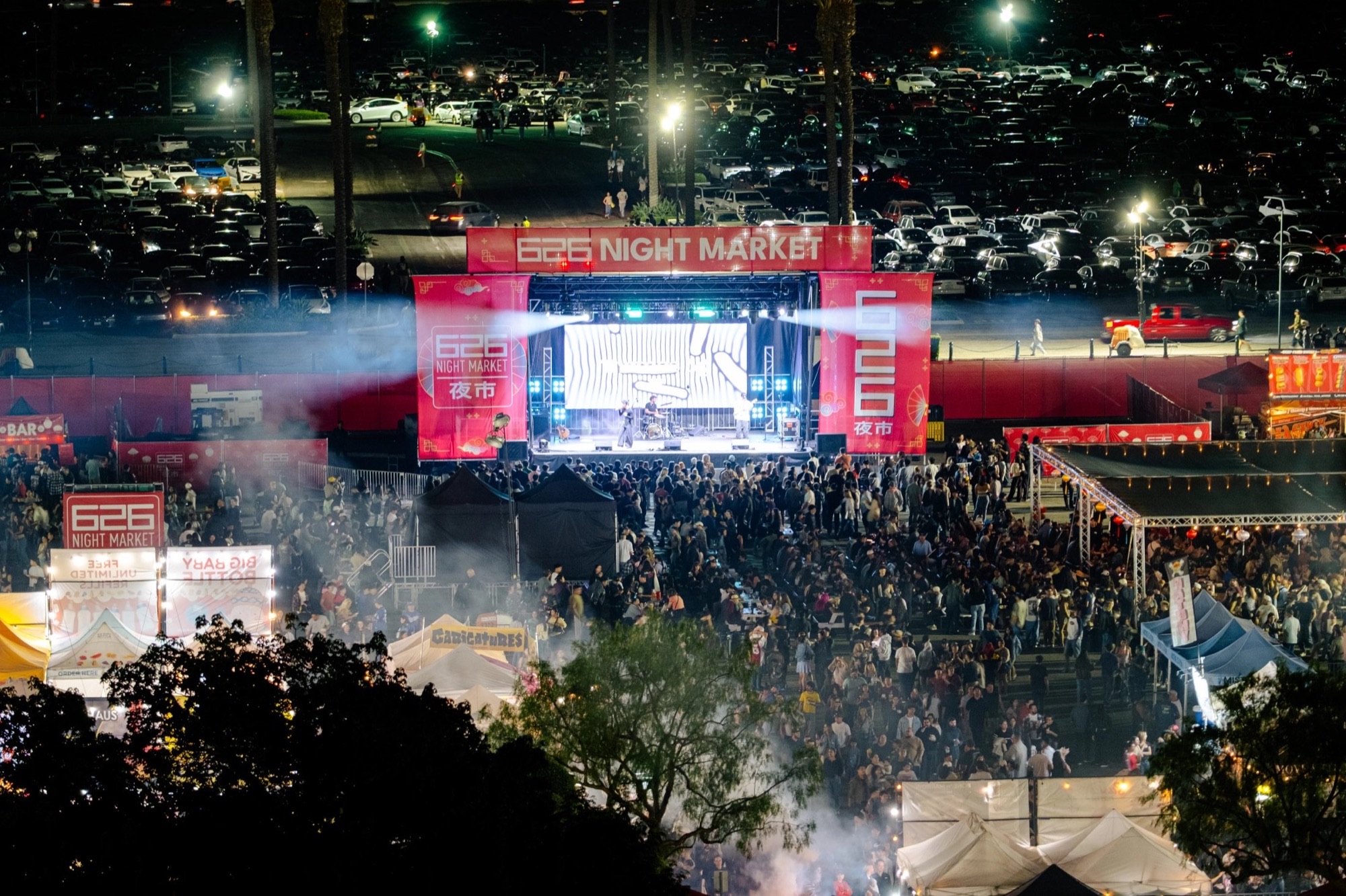 Nighttime crowd and stage at 626 Night Market on fairgrounds grounds.