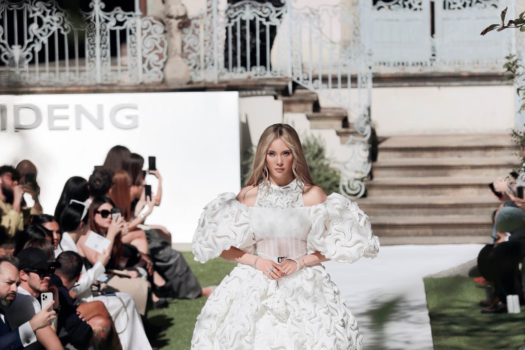 Eileen Gu walks the Bosideng SS24 runway in a white sculpted gown during Milan Fashion Week.