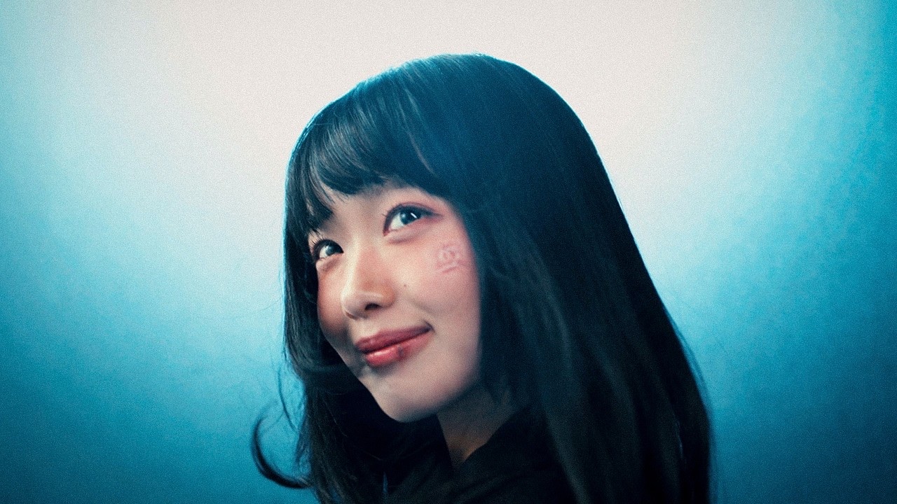 Korean singer-songwriter HANRORO looks upward in a blue-lit still from the Game Over? music video.