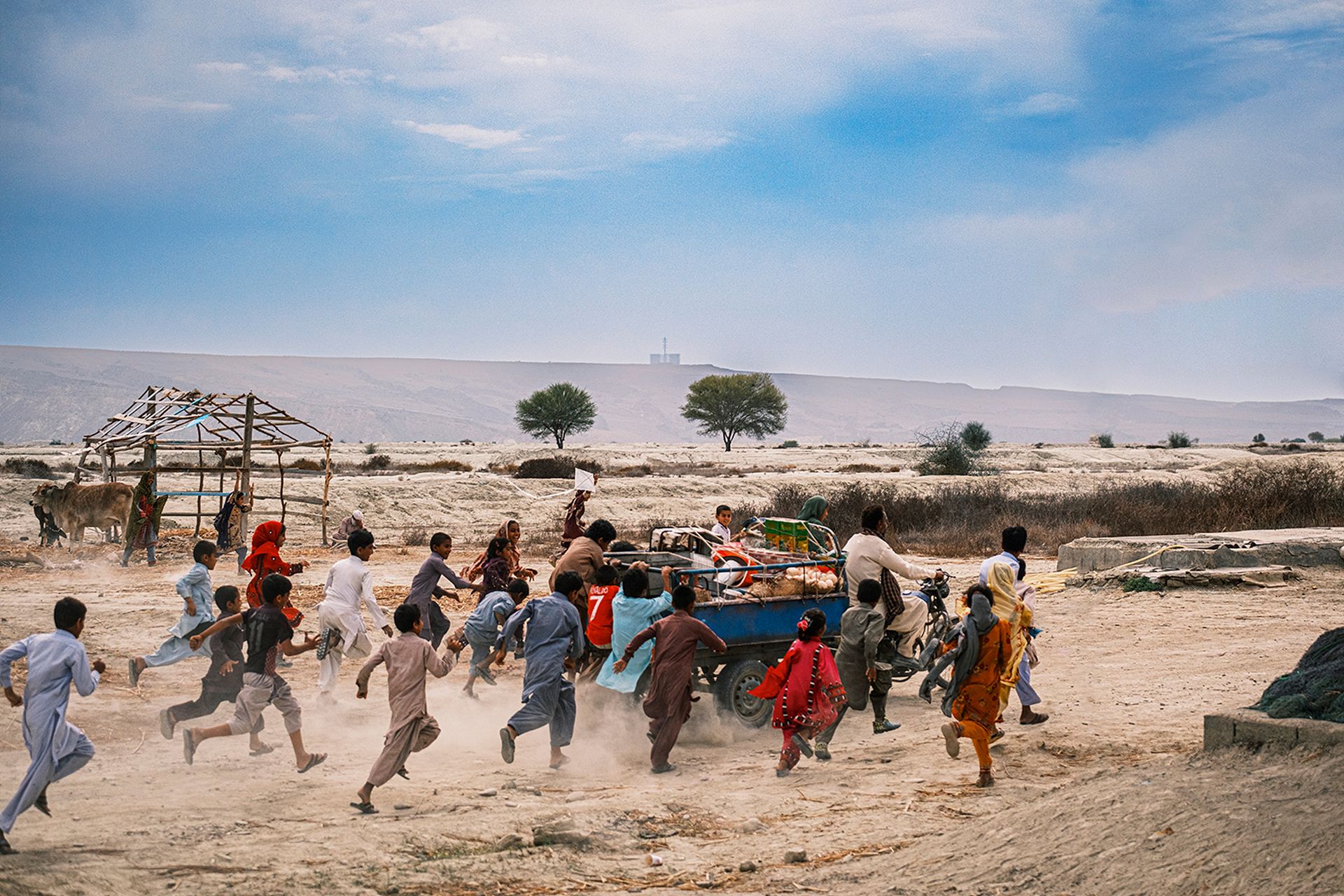Children run through dust beside a small truck in a dry landscape in Majid Majidi's Midday Meal.