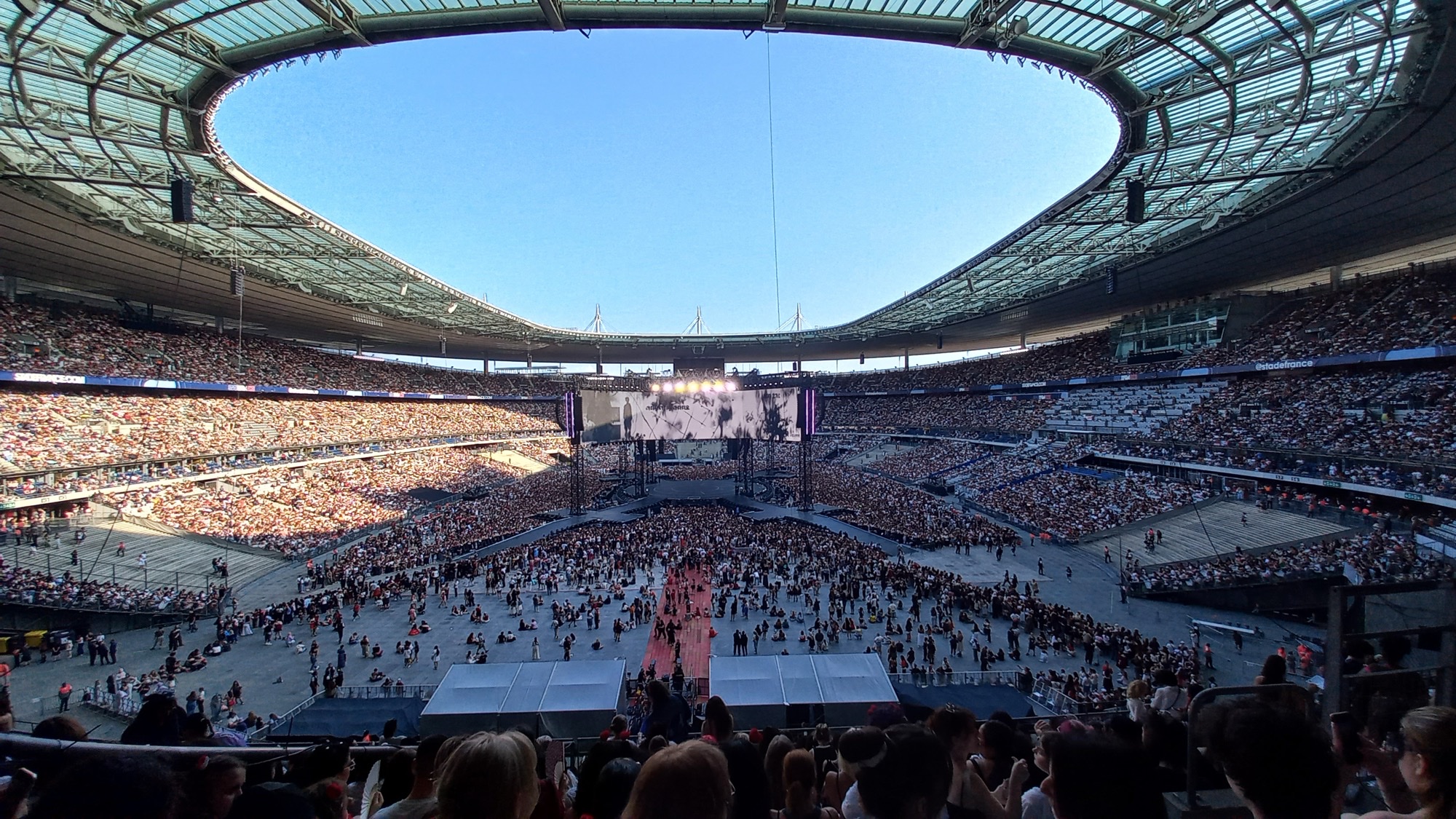 Stade de France in daylight during BTS Arirang World Tour, a packed bowl around a long stage and a video screen.