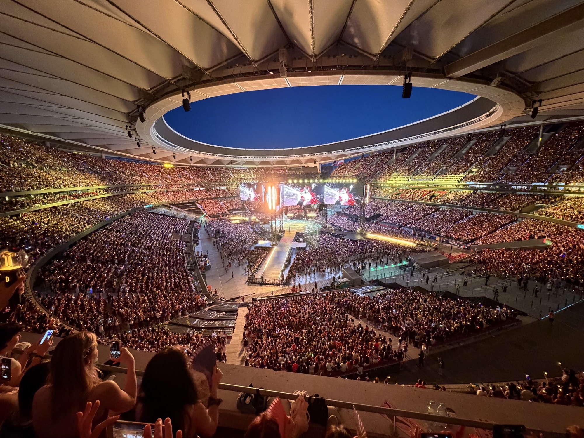 Packed night stadium during BTS Arirang World Tour in Madrid, with a glowing lightstick crowd filling the stands around a long runway stage.