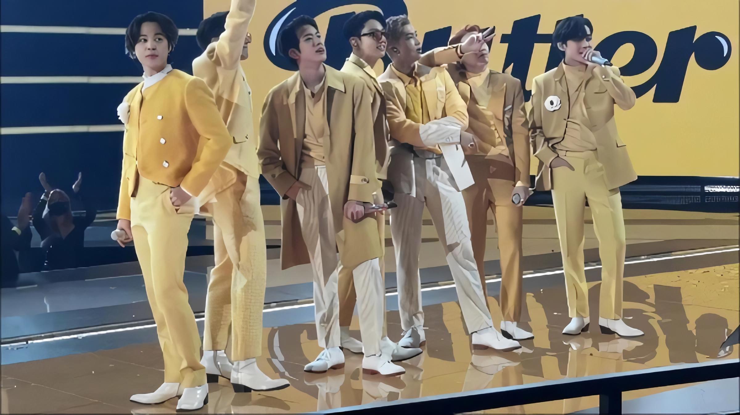 BTS performing Butter on stage in yellow suits under a Butter backdrop at the 2021 American Music Awards.