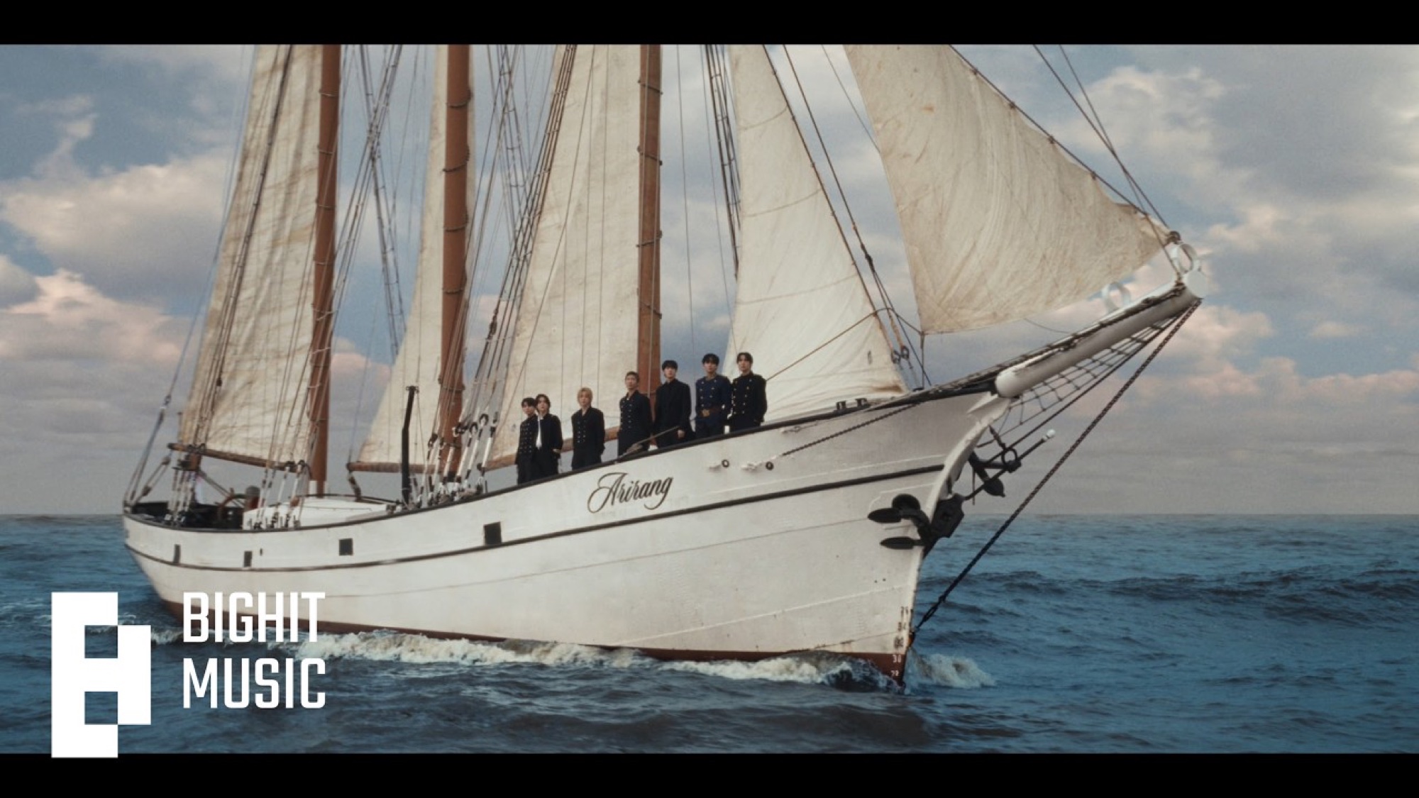 BTS standing on the deck of a white sailing ship labeled Arirang at sea in the SWIM music video.