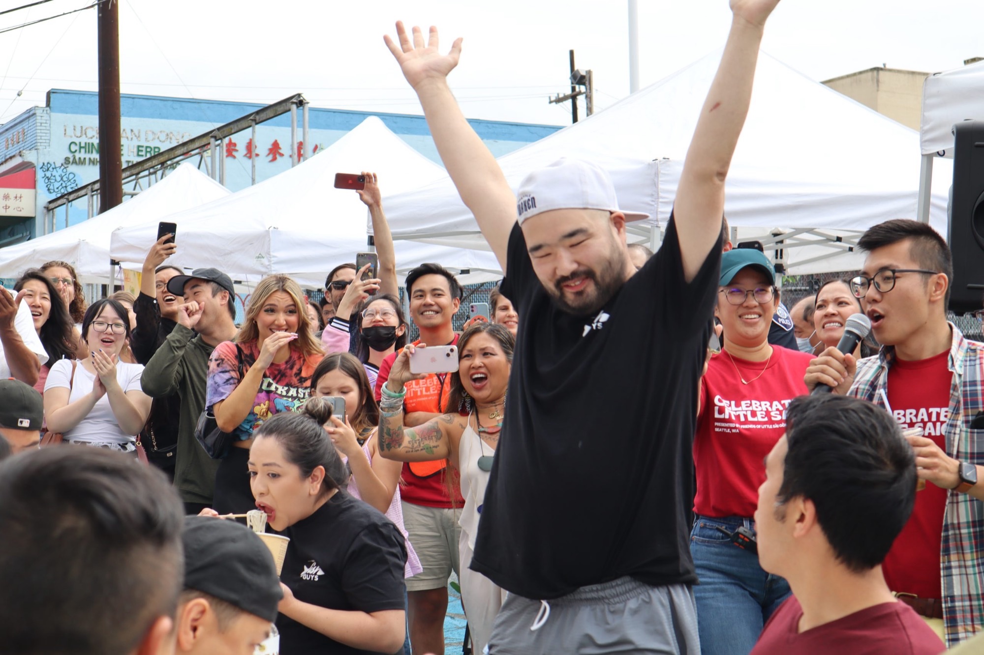 Crowd and volunteers in Celebrate Little Saigon shirts cheer during a food contest at Seattle’s Little Saigon street festival.