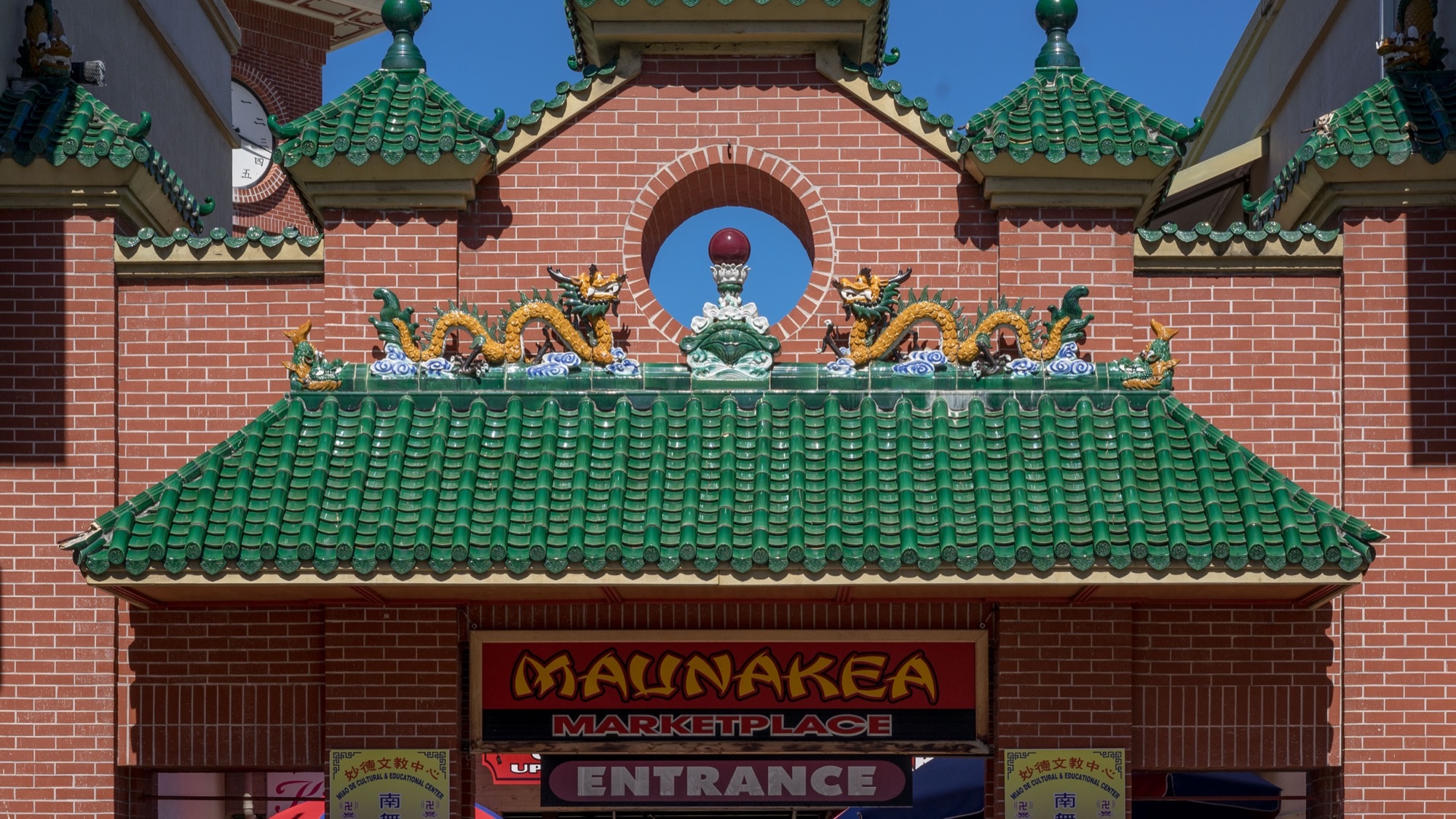 Green-tiled dragon roof and entrance sign at Maunakea Marketplace in Honolulu Chinatown.
