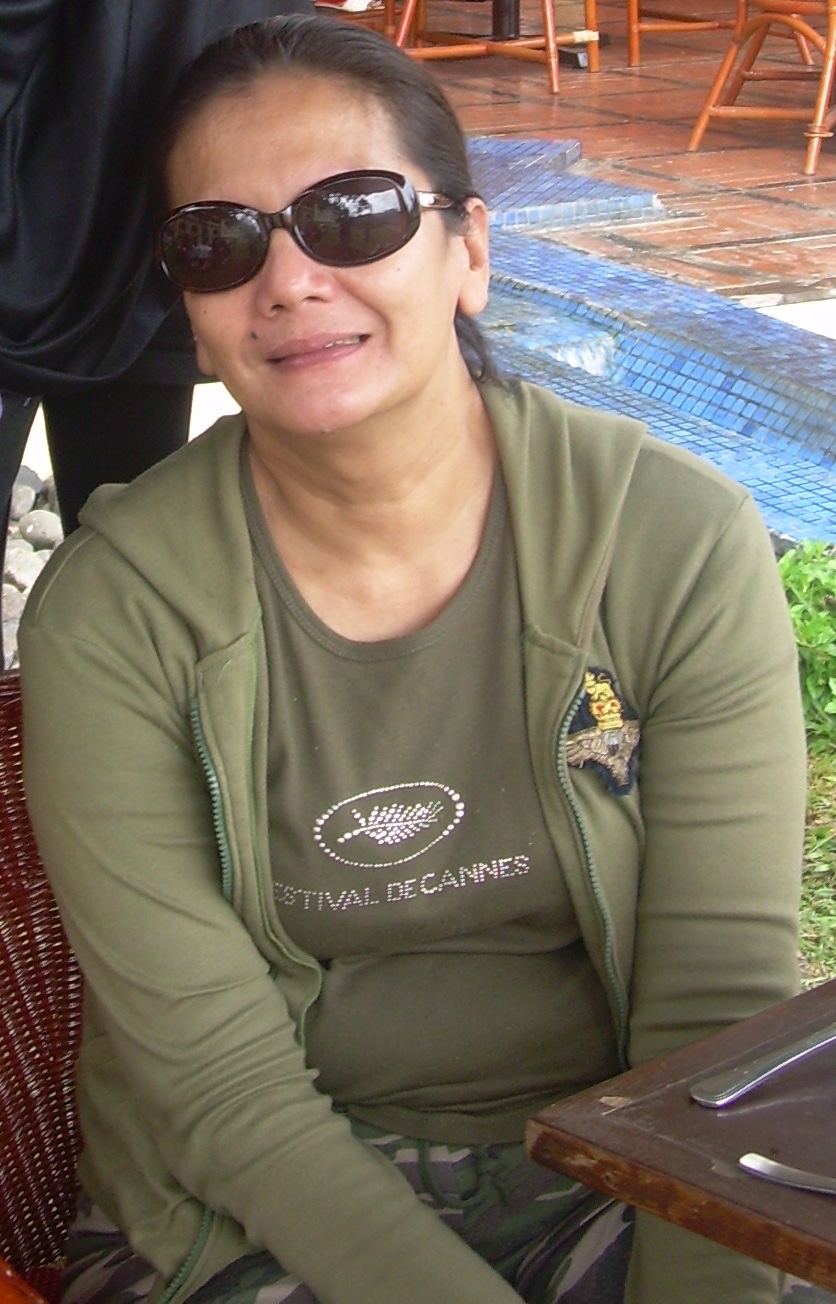Christine Hakim seated outdoors in Bukittinggi in 2008, in sunglasses and an olive hoodie over a Festival de Cannes T-shirt.