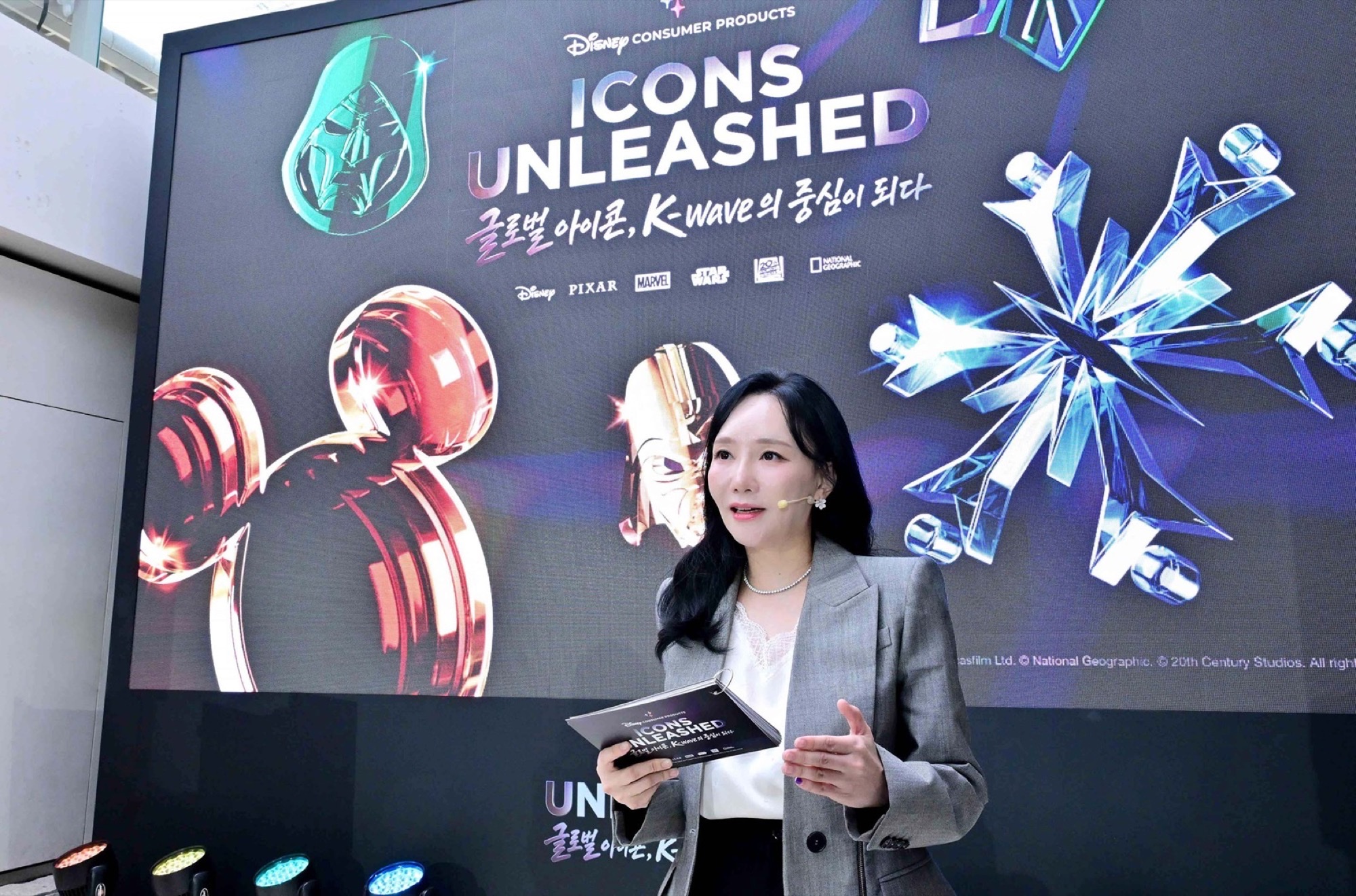 Disney Korea consumer products chief presenting at the Franchise Showcase 2027 under an Icons Unleashed K-Wave screen.