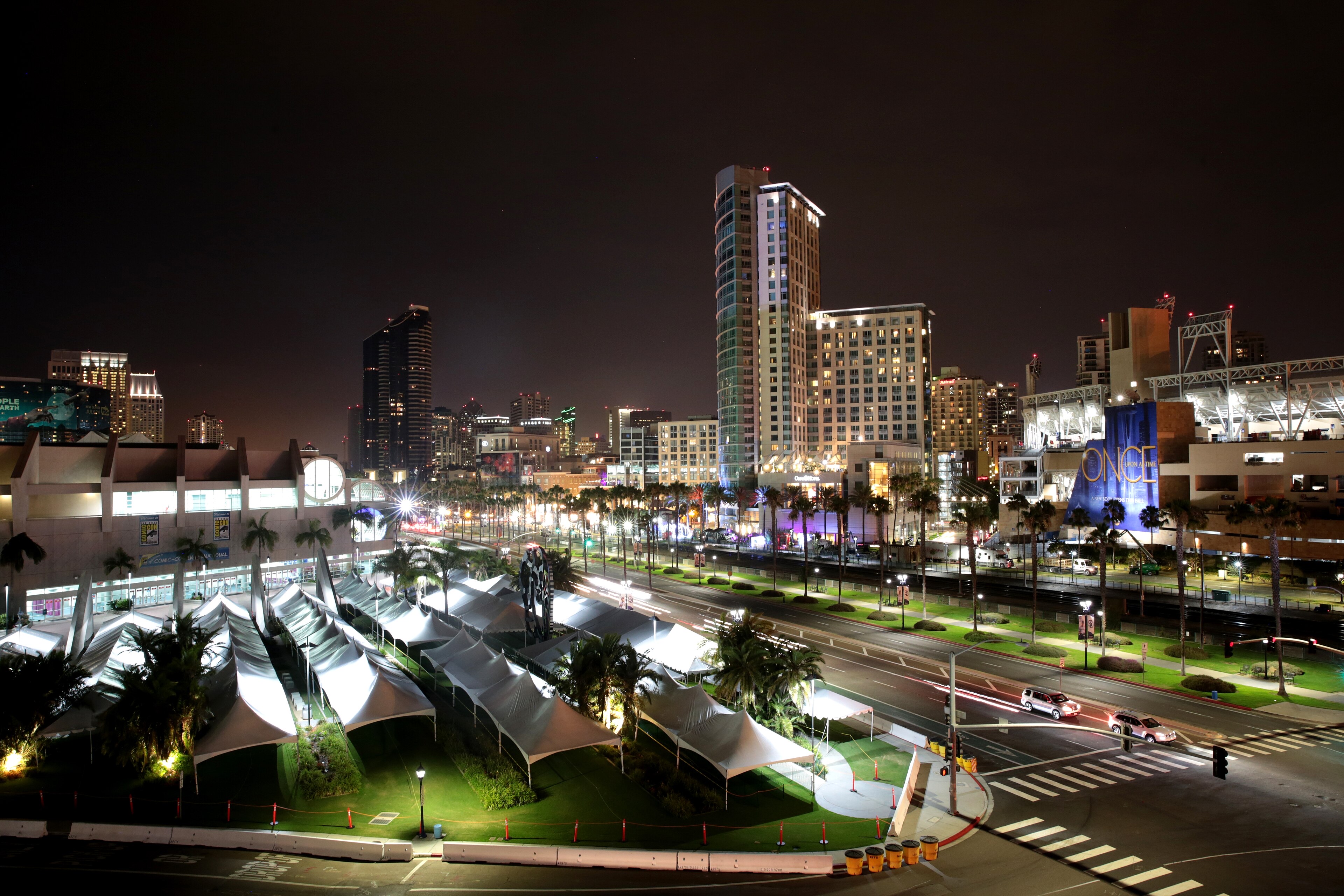 San Diego Convention Center at night with lit sail roofs and palm trees along the waterfront.