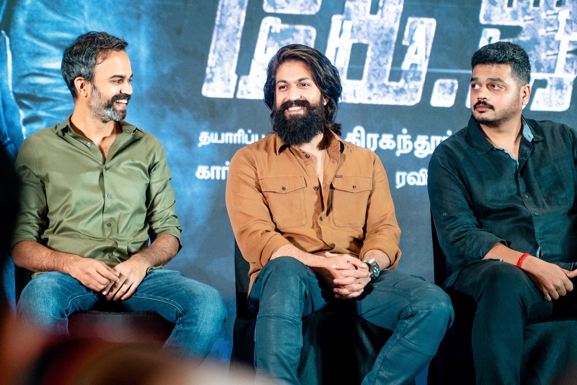 Director Prashanth Neel and actor Yash promote KGF Chapter 2 at a Chennai press event, seated with microphones against a promotional backdrop.