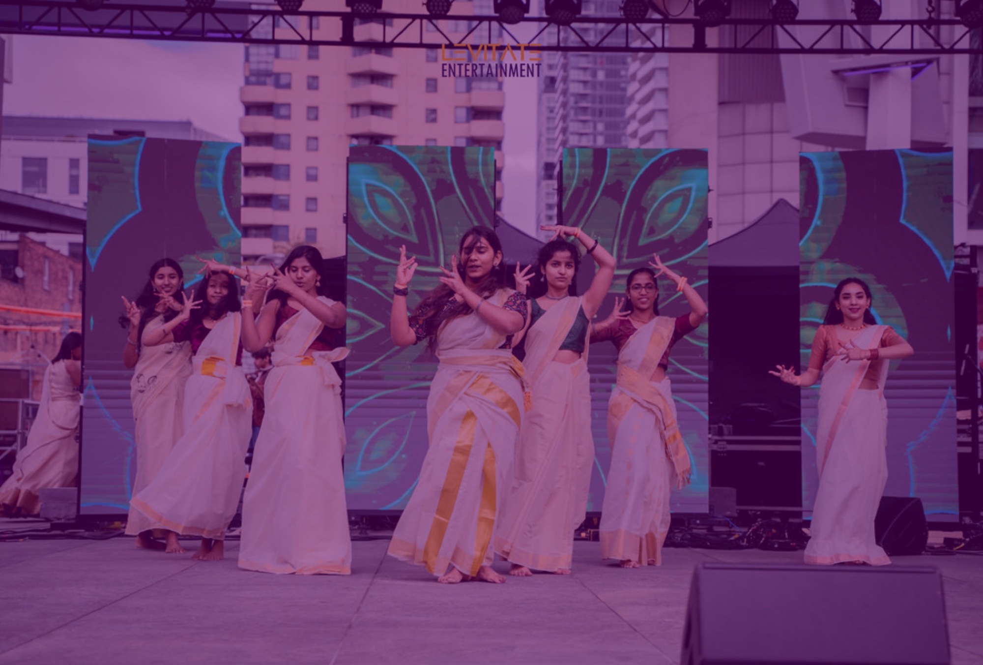 Dancers in cream and gold kasavu sarees perform on an outdoor stage at Maha Onam in downtown Toronto.