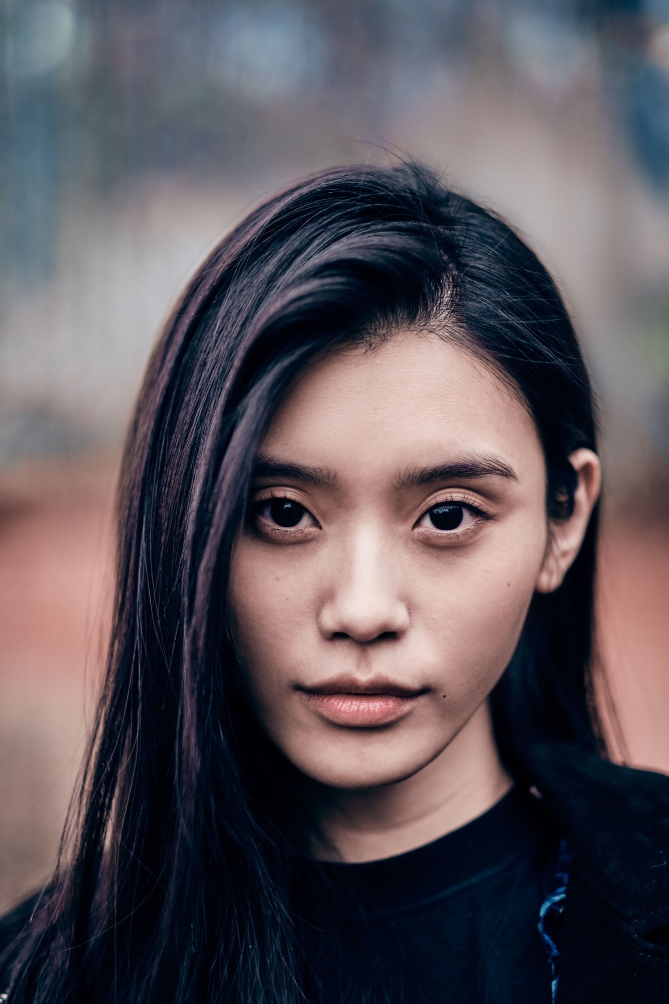 Ming Xi looking into the camera at Paris Fashion Week Autumn/Winter 2019, long dark hair framing her face, in a dark crewneck.