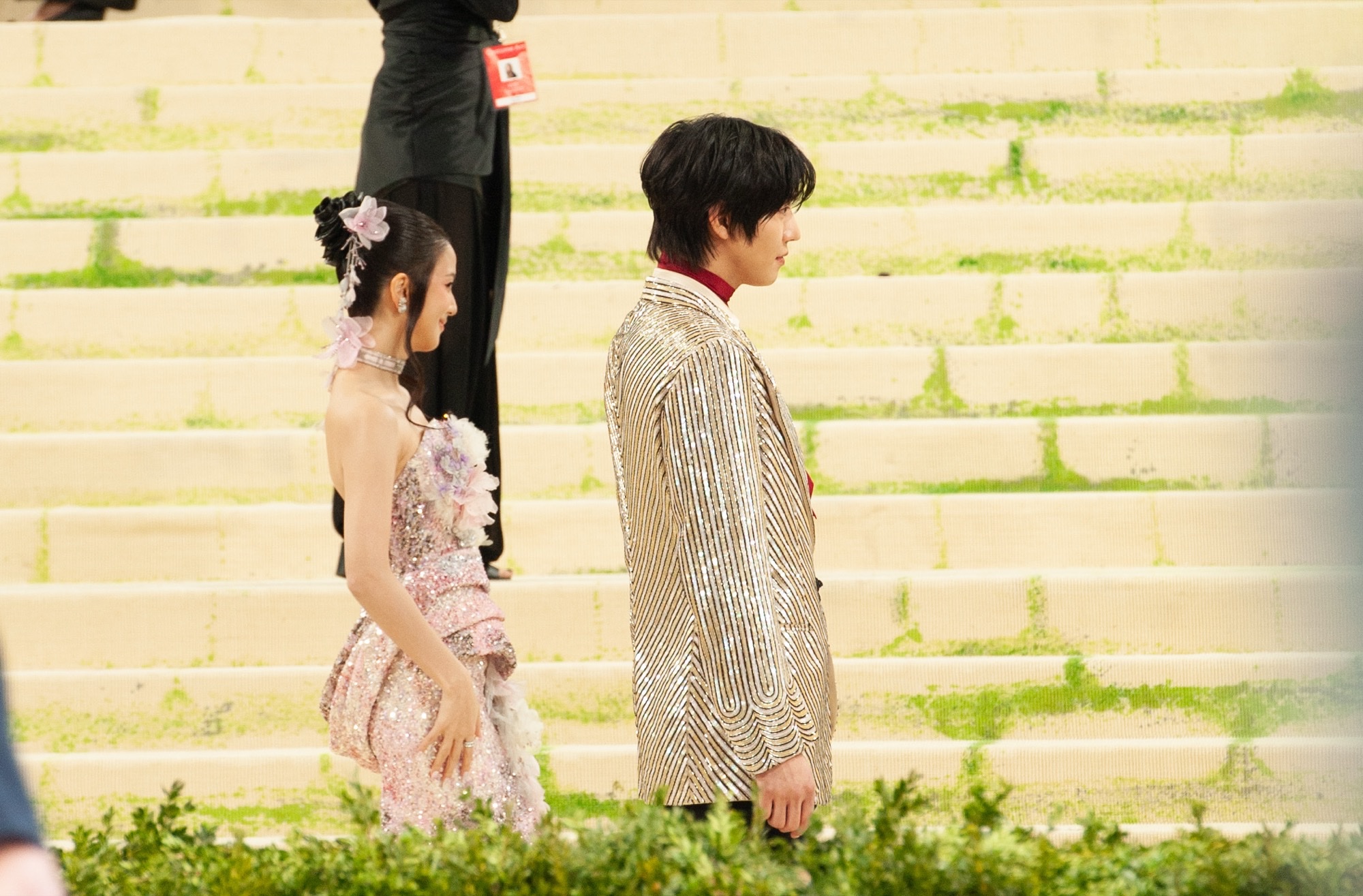 Ahn Hyo-seop walks the 2026 Met Gala steps in a silver striped Valentino suit and red scarf, with Jisoo behind him.