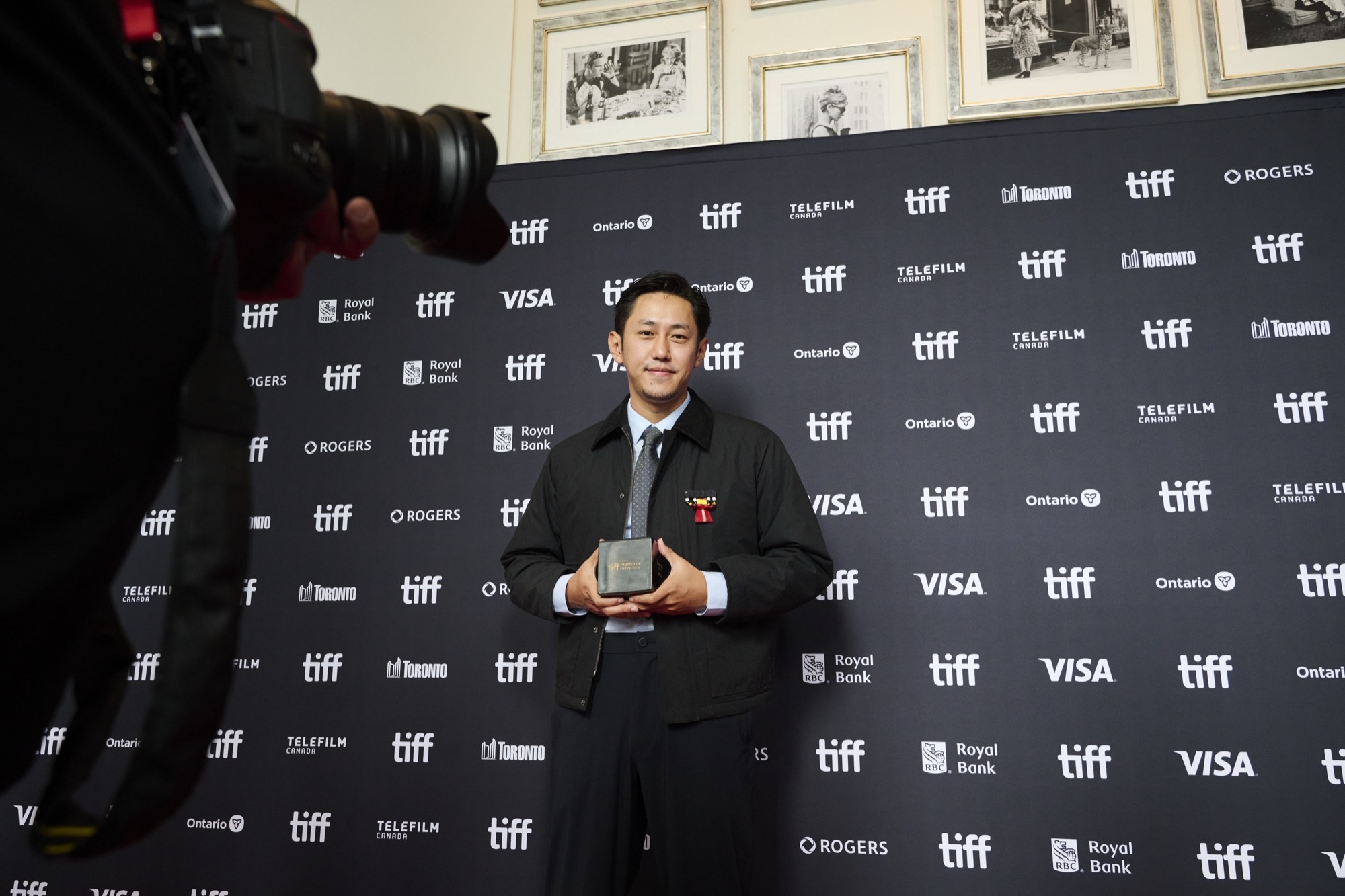 Theja Rio holds his TIFF Platform Prize award in front of a festival step-and-repeat backdrop in Toronto.