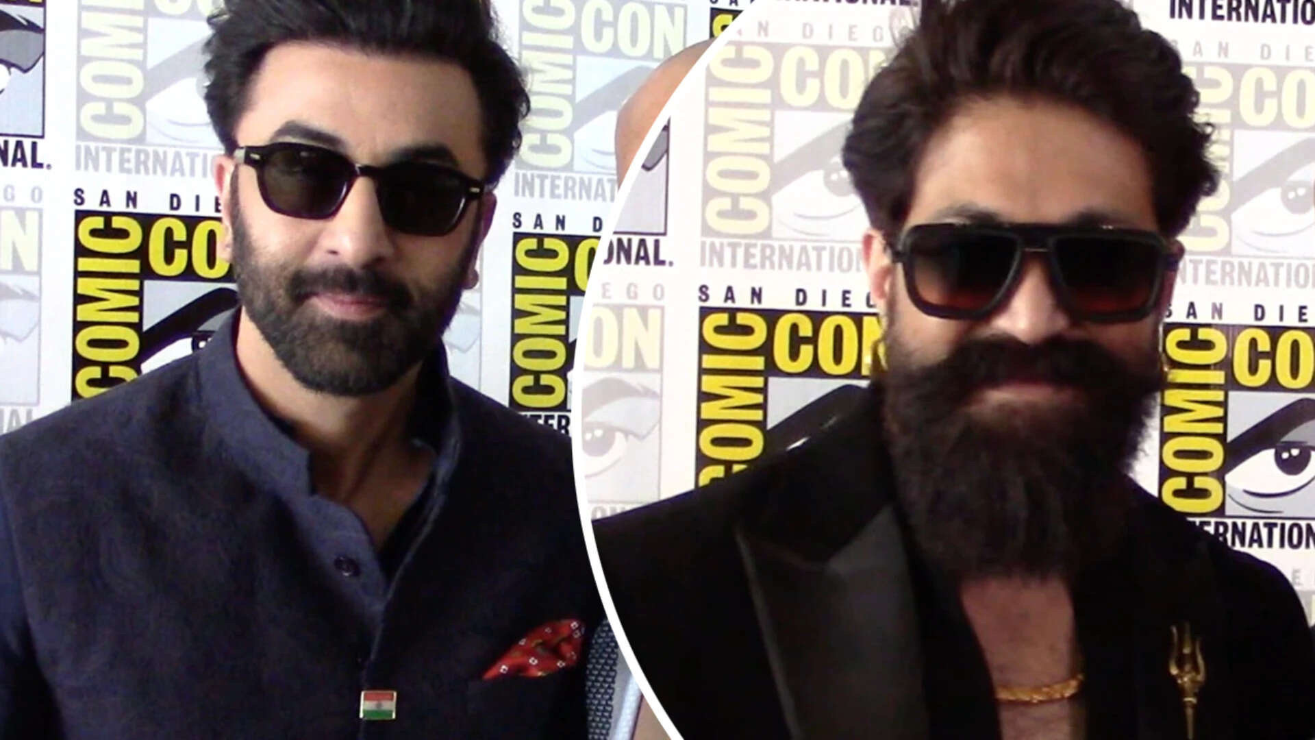 Ranbir Kapoor in a navy bandhgala with Tiranga lapel pin and Yash in black with sunglasses, posing against San Diego Comic-Con International backdrops.