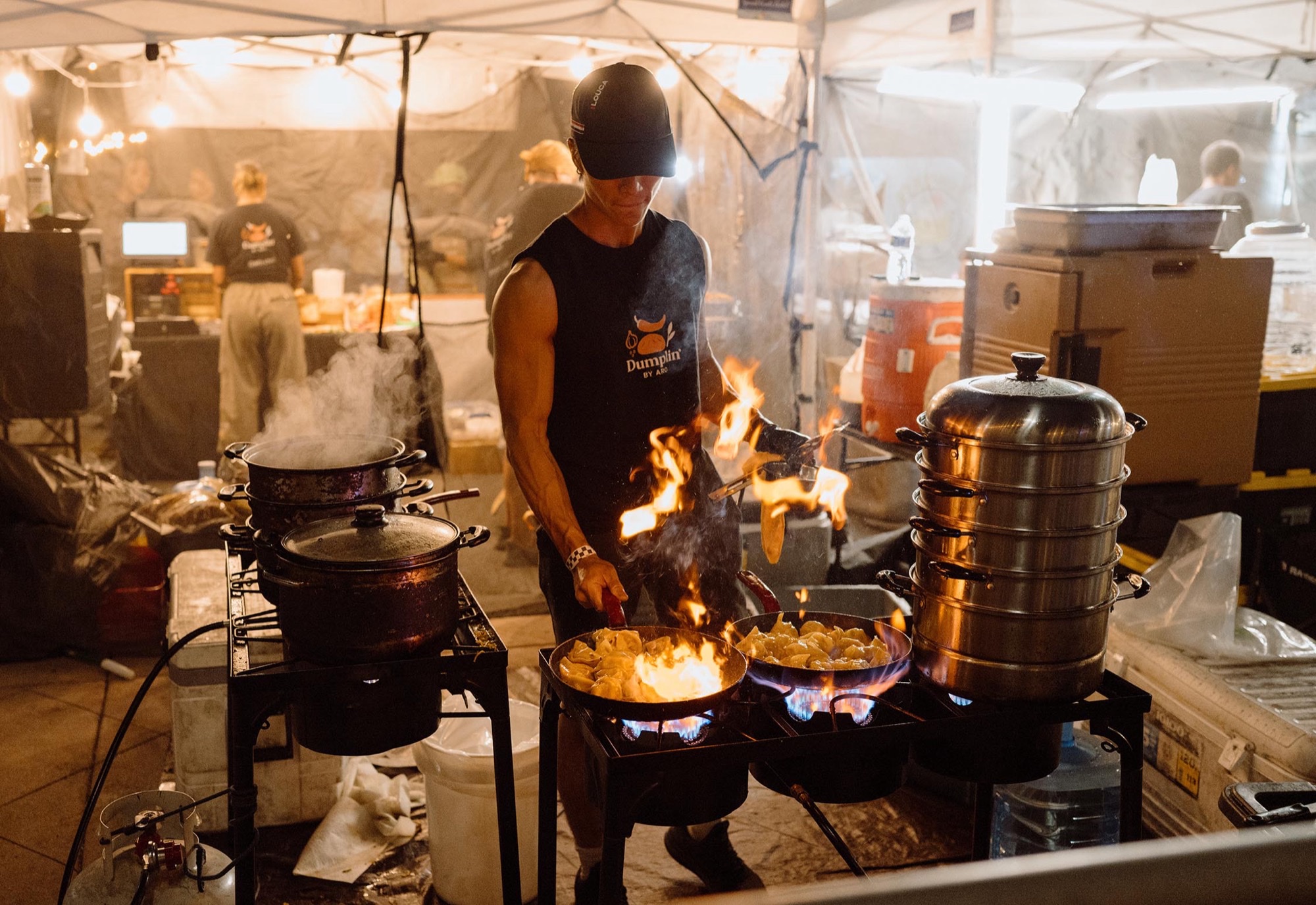 A dumpling vendor flames pans under a tent at San Gabriel Dumpling and Beer Fest.