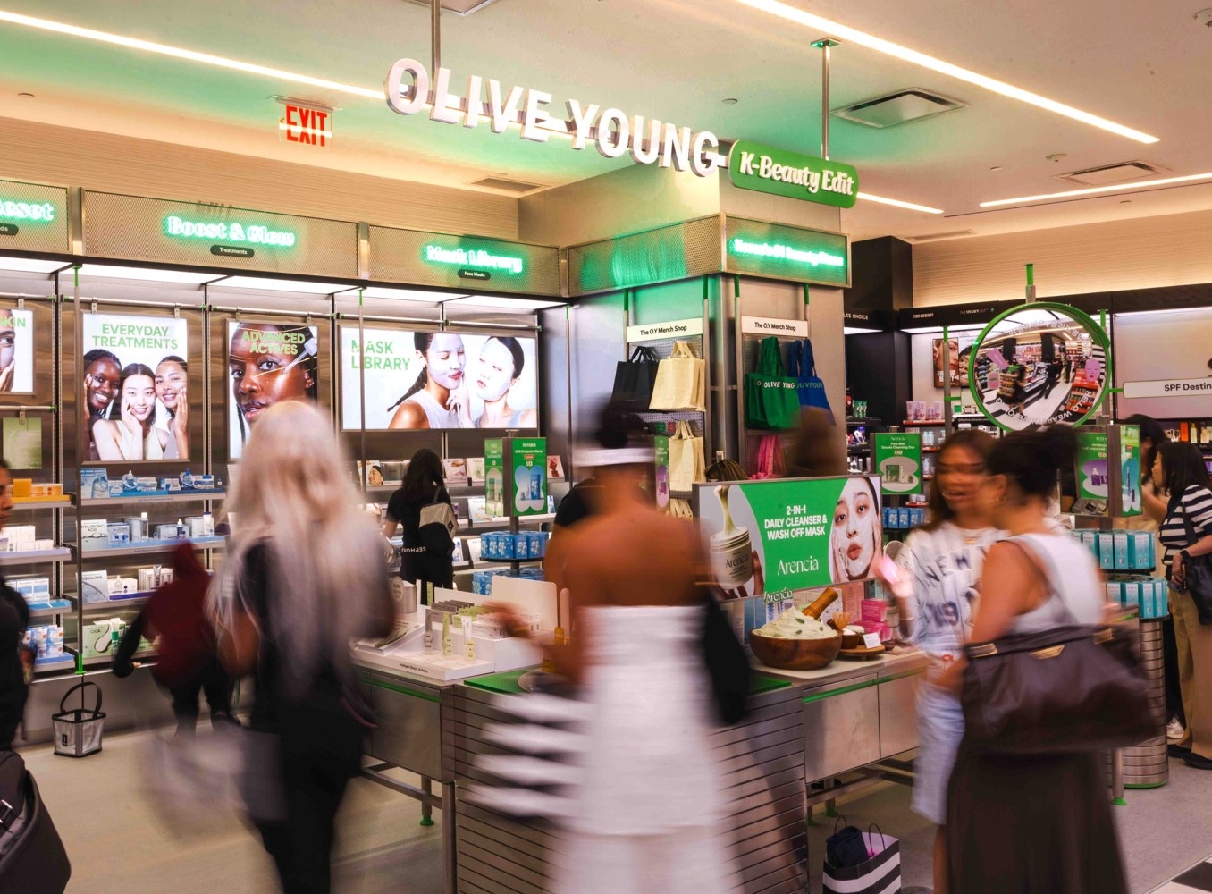 Shoppers browse the Olive Young K-Beauty Edit inside a Sephora, with Boost & Glow and Mask Library signage and a Sephora striped bag in the aisle.