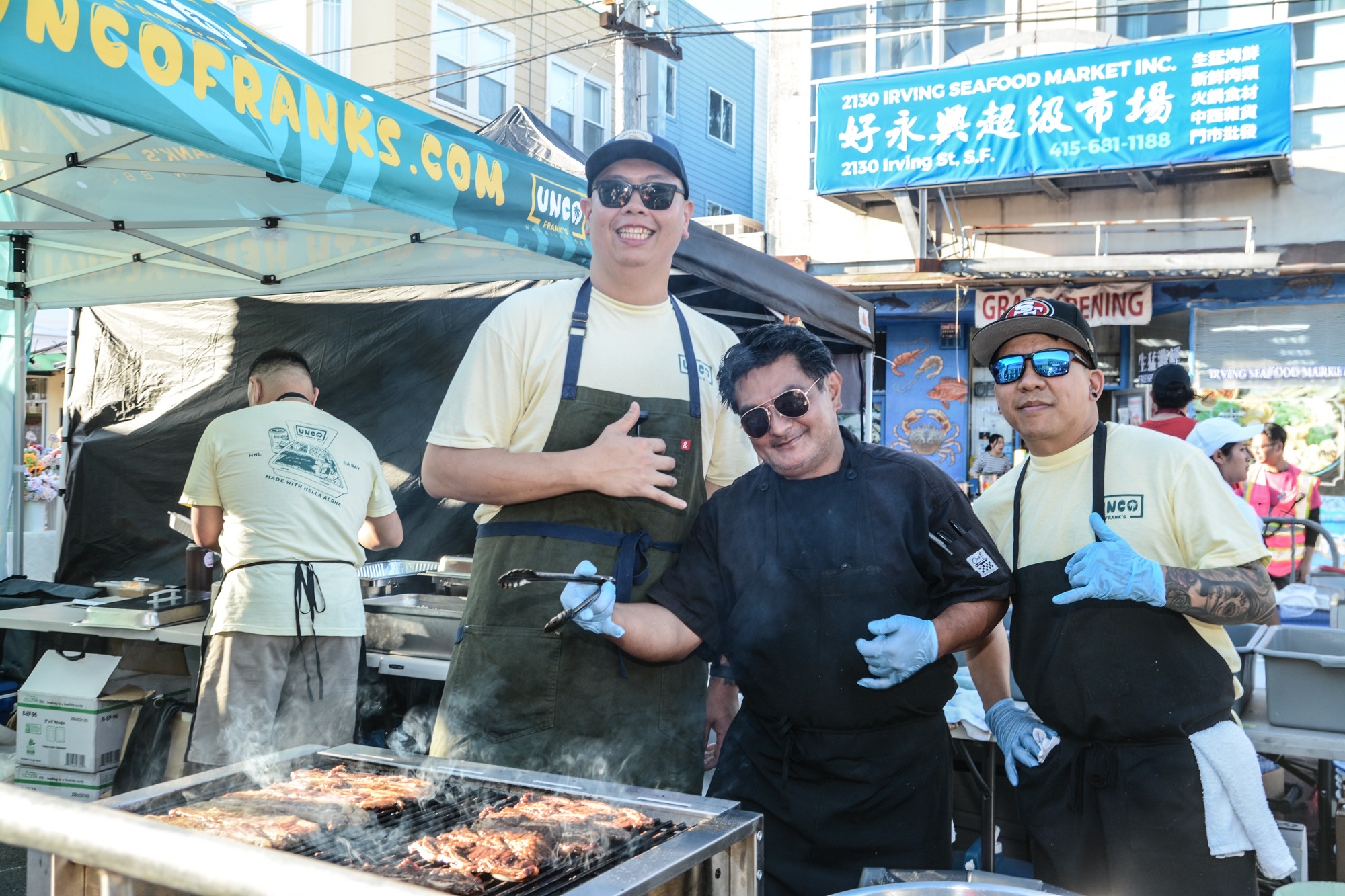 Food vendors grilling on Irving Street during a Sunset Night Market, with the Irving Seafood Market storefront behind them.