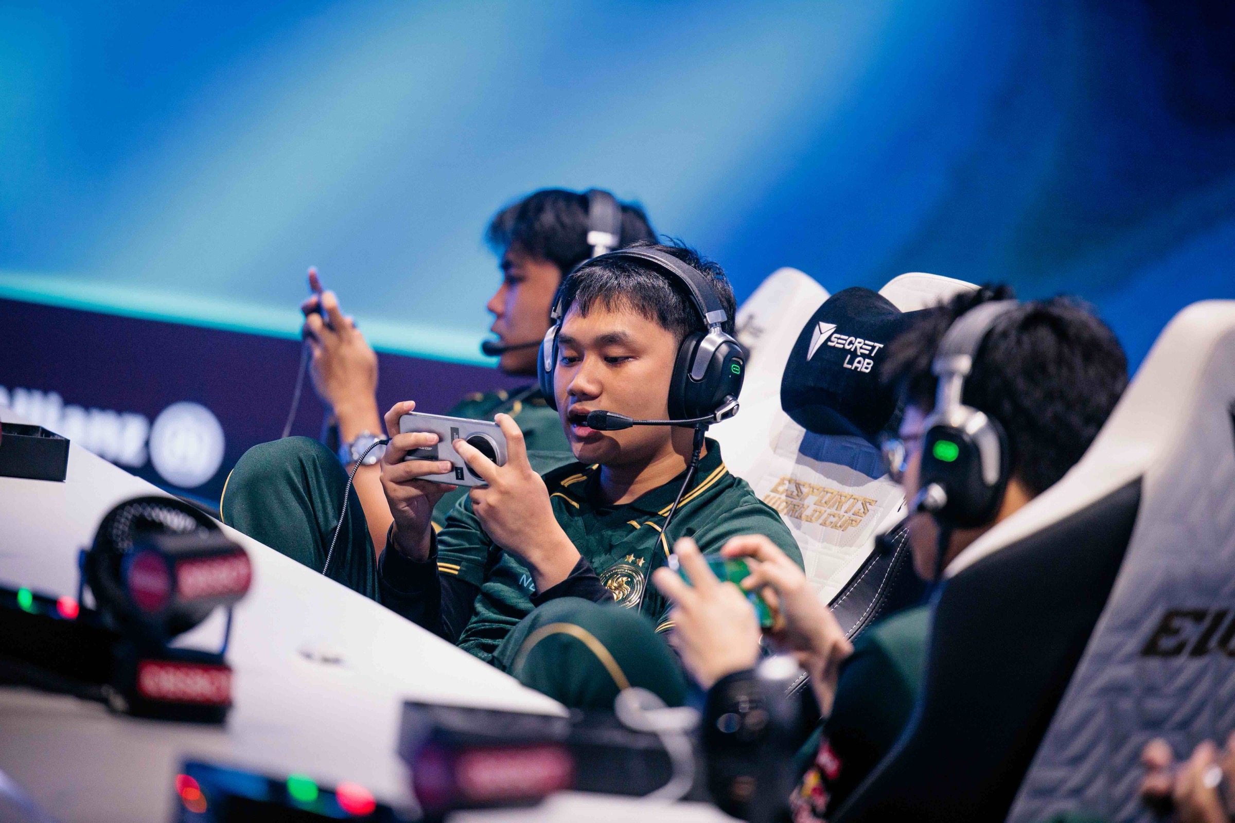 Mobile Legends players compete on phones with headsets at the Esports World Cup stage in Paris during the Mid-Season Cup.