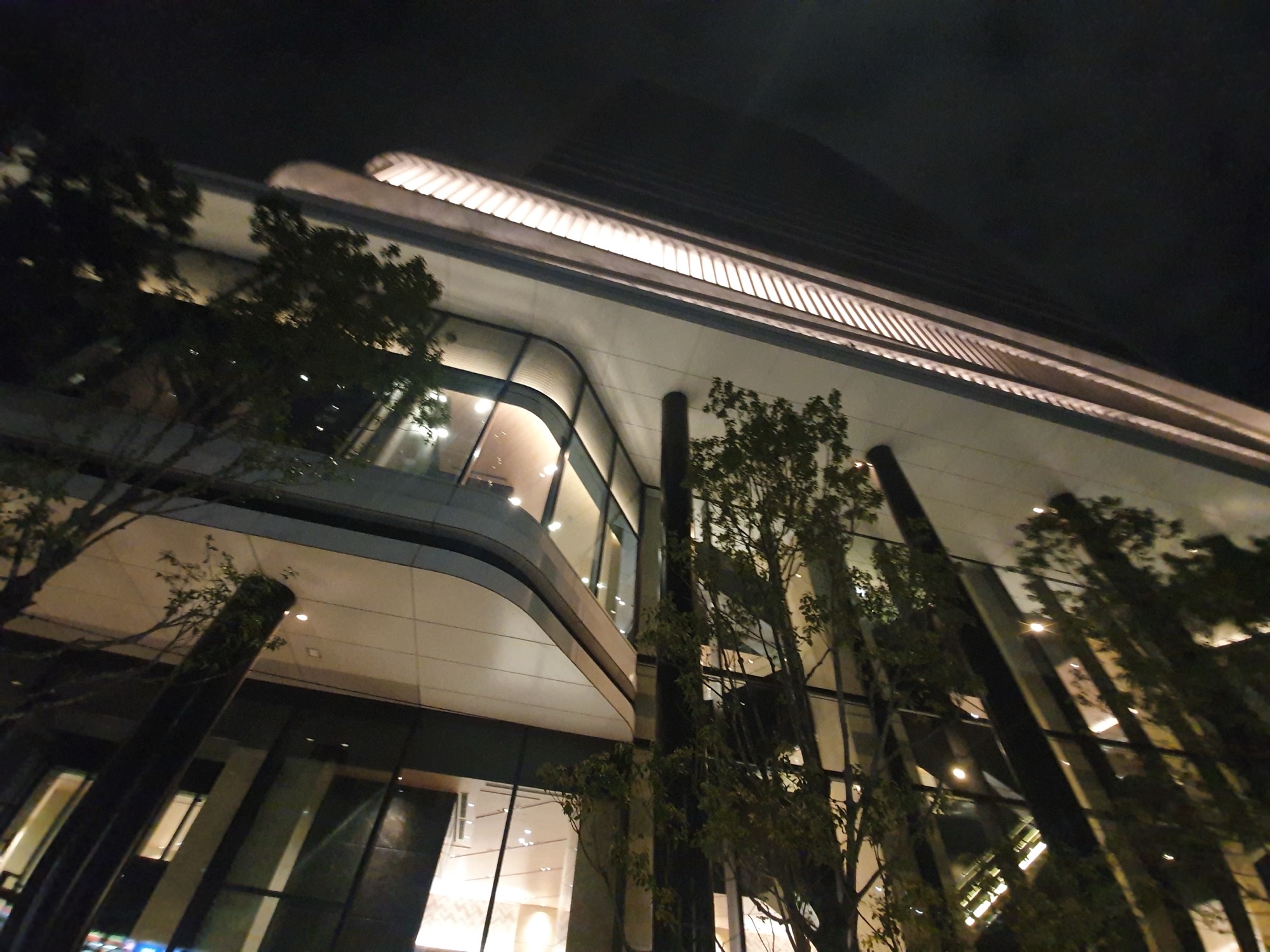 Night exterior of the Tokyo Metropolitan Industrial Trade Center Hamamatsucho, glass facade lit from inside, the venue that hosts TIFFCOM.