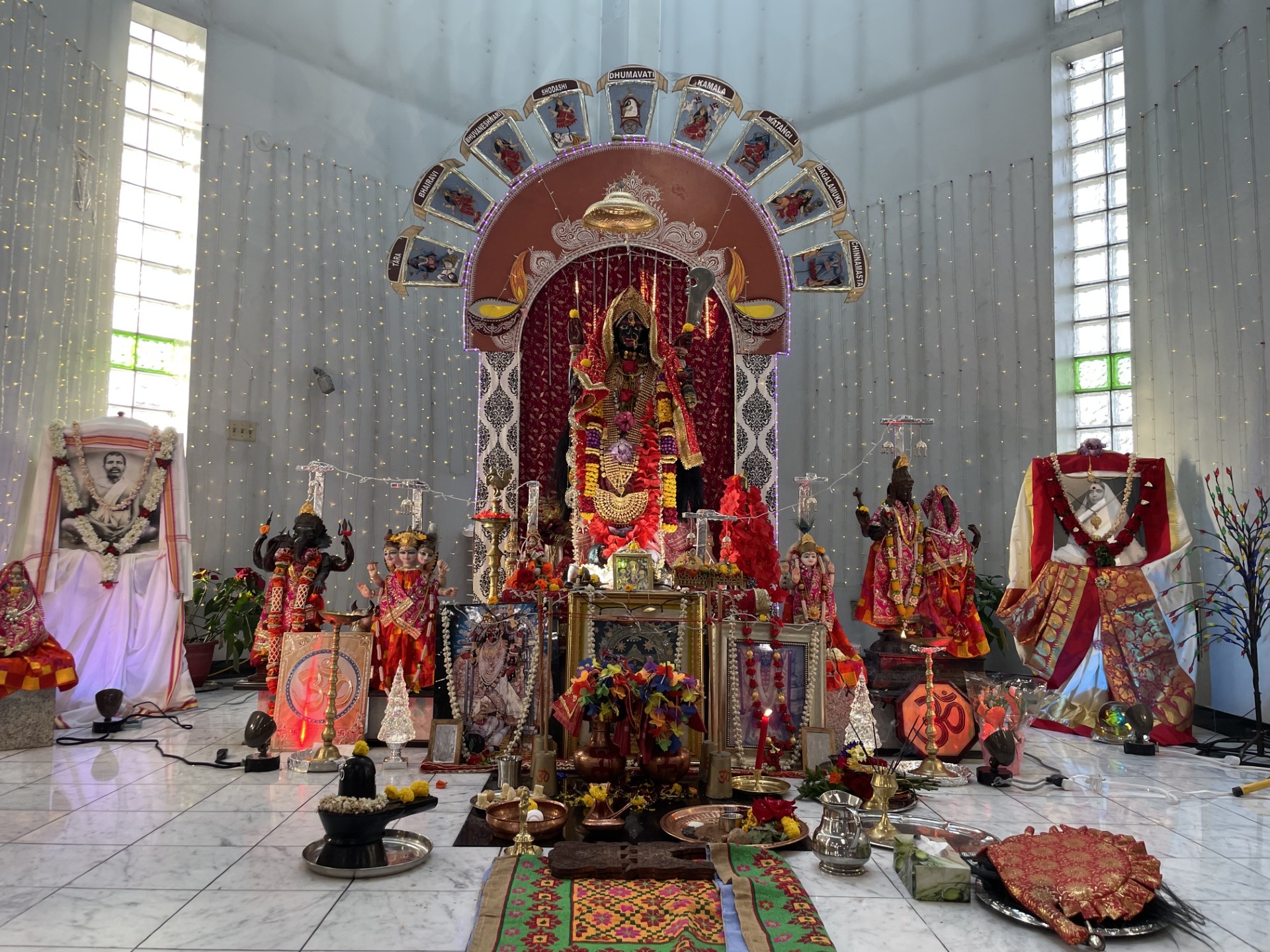 Interior of Toronto Kalibari in Mississauga, with the central Kali altar, Dashamahavidya arch, and Ramakrishna and Sarada Devi shrines under festival lights.