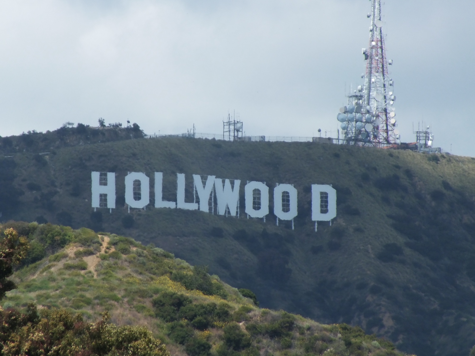 The Hollywood Sign on Mount Lee in Los Angeles, with a telecommunications tower on the ridge beside it.