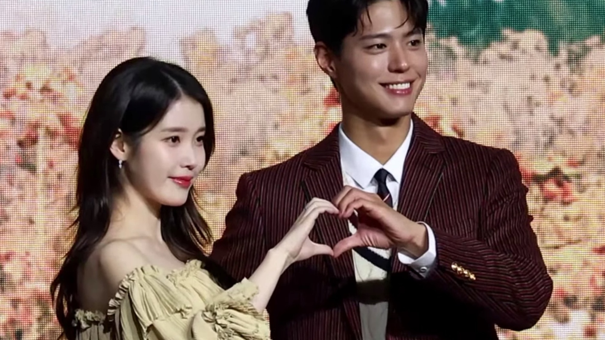 IU and Park Bo-gum form a heart with their hands at a When Life Gives You Tangerines press conference in March 2025.