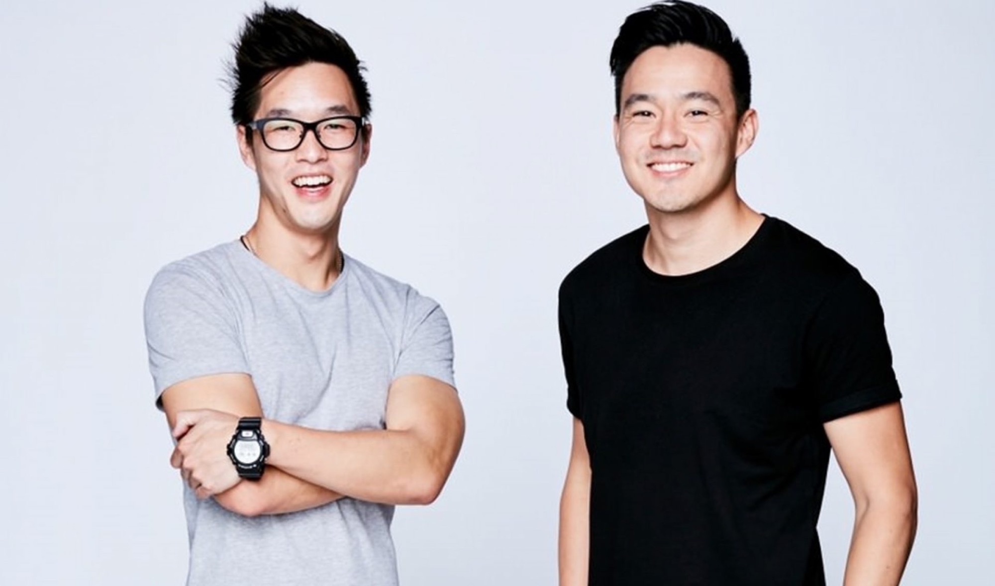 Wong Fu Productions co-founders Philip Wang and Wesley Chan in a studio portrait, Wang in glasses with arms crossed.