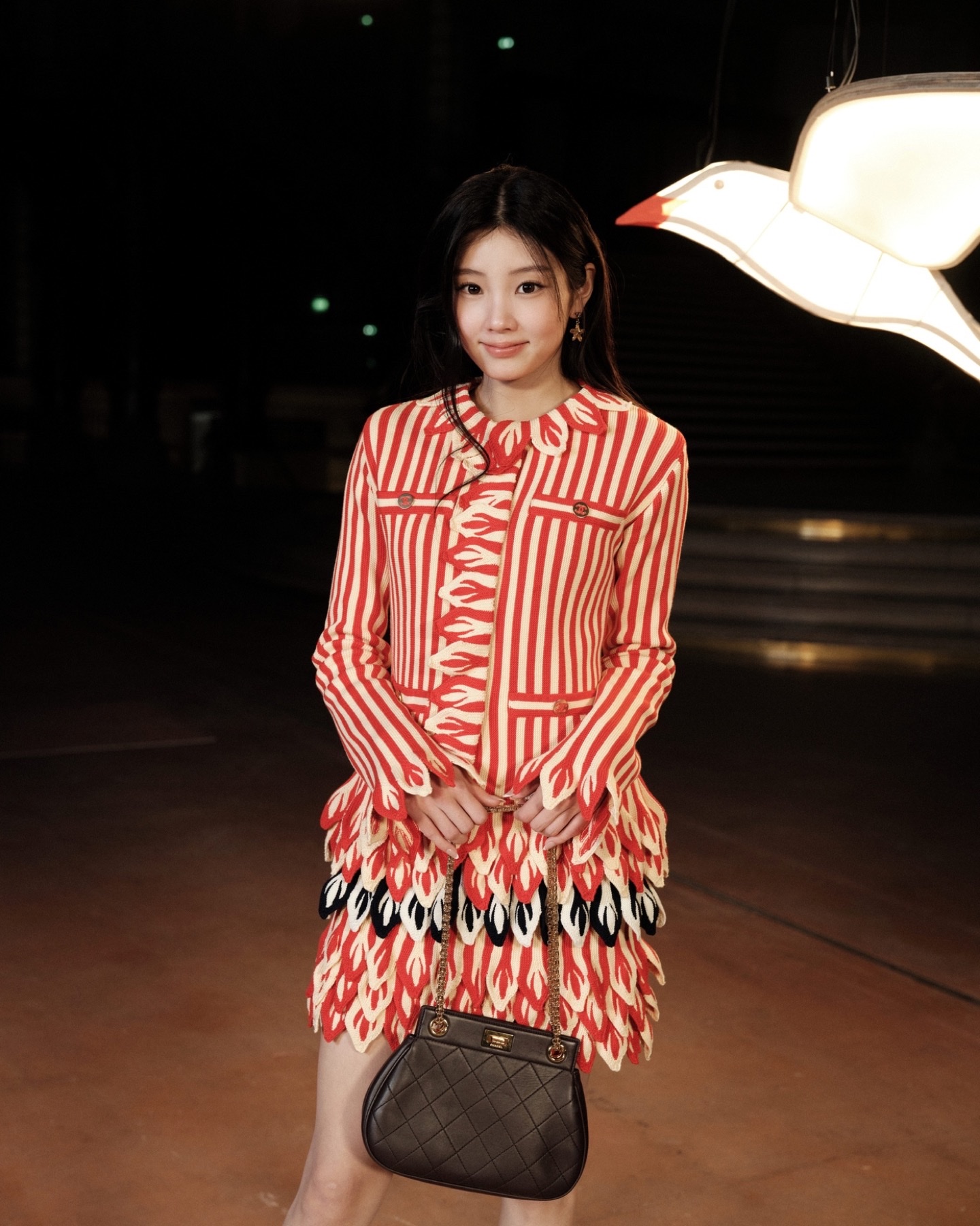 ILLIT's Wonhee in a red-and-white striped Chanel Cruise 2027 look with a quilted bag at the Grand Palais for the Spring/Summer 2027 show.